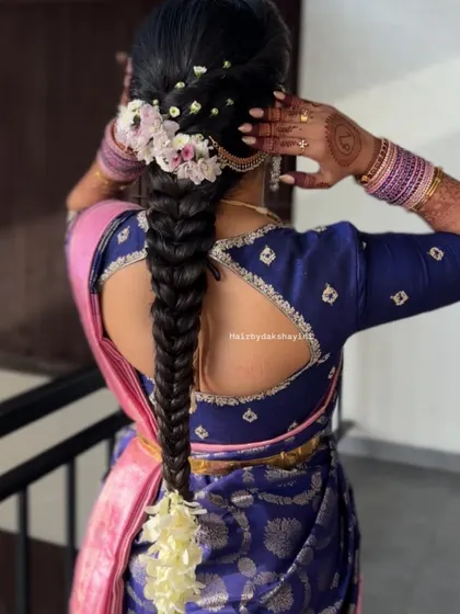 A neat and classic South Indian fishtail braid, adorned with fresh flowers along the top and a jasmine bunch at the end, perfect for a traditional event.