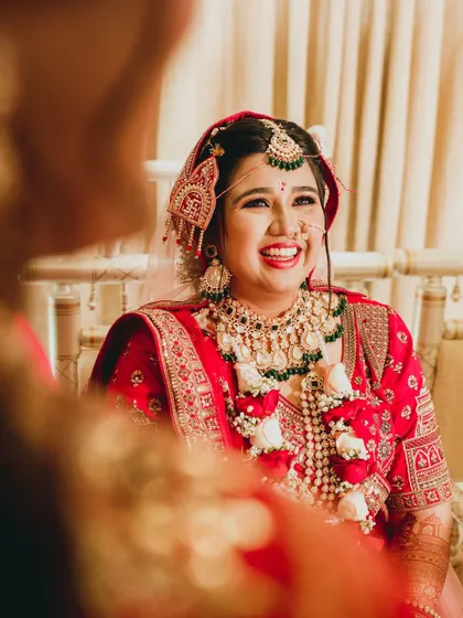 A beautiful, candid close-up of the bride's radiant smile during her wedding ceremony. This over-the-shoulder shot creates a sense of intimacy, as if we are sharing in her personal moment of joy.