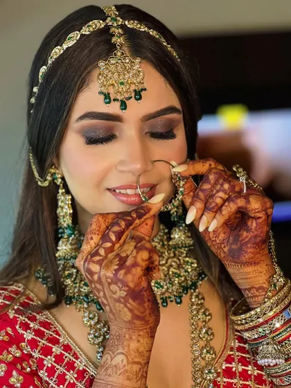 A candid moment capturing the beauty of the bridal details. The smokey eye makeup enhances her gaze, while the soft contouring defines her features.