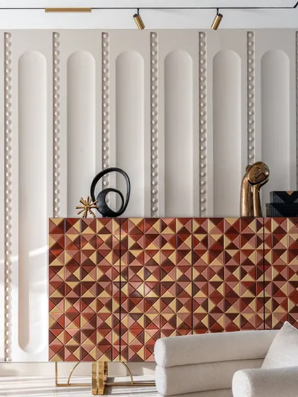 This custom console with a geometric wood inlay is a piece of functional sculpture. Set against a wall with subtle 3D paneling, it demonstrates our commitment to bespoke details that elevate a space beyond the ordinary.