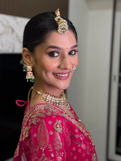 A close up of this bride's joyful expression. The makeup features a clean, dewy base, soft pink lips, and a neat bun, creating a fresh and youthful bridal look.