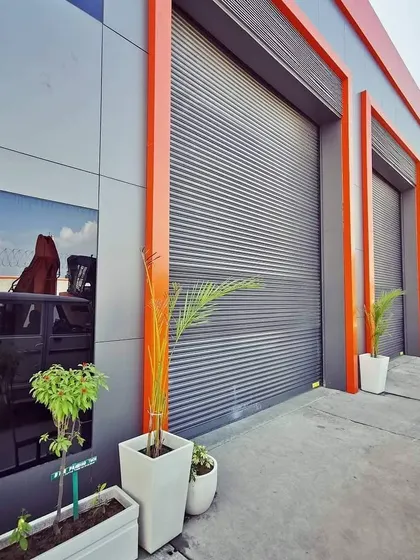 The service bay area, featuring large rolling shutters framed in orange. The design ensures that even the most functional parts of the building are visually integrated with the overall architectural concept.
