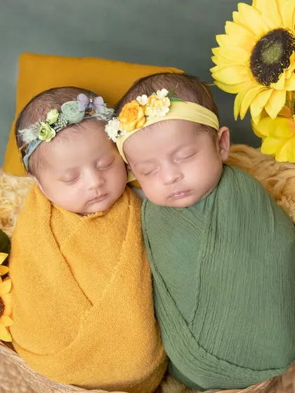 Two little sunflowers, born together. This photo showcases a beautiful setup for newborn twins, nestled together in a basket.