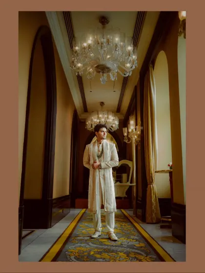 A solo portrait of the groom looking dapper in his wedding sherwani, captured in a grand hotel corridor.