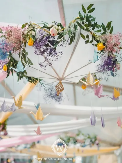 Details from a pastel-themed Mehendi, featuring an umbrella adorned with flowers and hanging origami birds. These delicate touches added a layer of playful elegance to the decor.