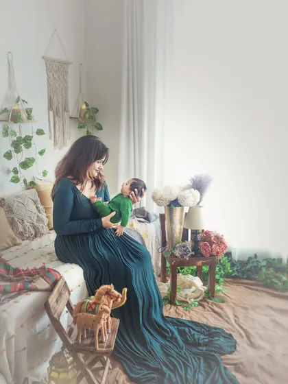 My Boho studio setup is designed to be a calm, beautiful space. Here, a mother holds her newborn, with the flowing green dress and natural light creating a serene, lifestyle portrait.