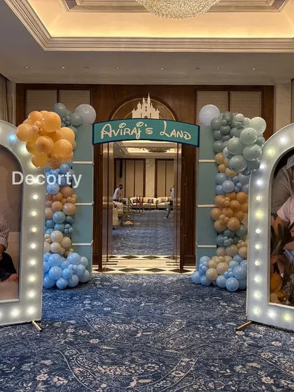 A grand entrance to 'Aviraj's Land', styled for a Disneyland-themed birthday. The doorway is framed with blue and gold balloon garlands, creating a magical entryway for all the guests.
