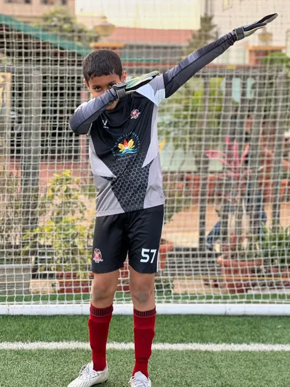Turning potential into performance. A young goalkeeper shows off his confidence with a dab after a good training session.