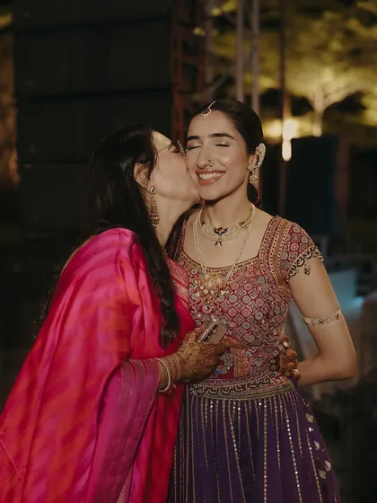 A mother's love. A tender kiss for her daughter, the mother's vibrant pink saree a beautiful pop of color next to the bride's intricate ensemble.