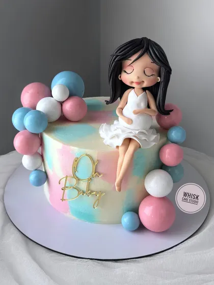 Your dream baby shower cake is here. This elegant cake features a beautiful, handcrafted figurine of a mom-to-be, surrounded by pink and blue balloons.