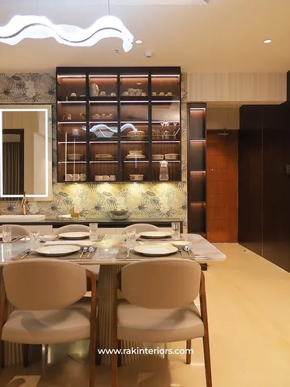 The dining area in Dr. Noushad's home, featuring a marble-top table, a large crockery unit with glass doors, and elegant wallpaper.