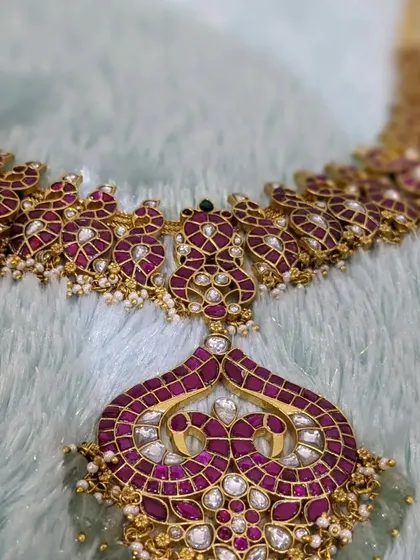 This pink Jadau uncut jewellery set has a pure brass base and is paired with Chaand Baali earrings and a matching maang tikka.