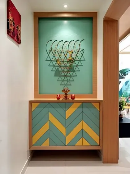 A vibrant and artistic foyer with a colorful chevron-patterned cabinet. The large frosted glass panel with a geometric design adds a unique Vastu or spiritual element.