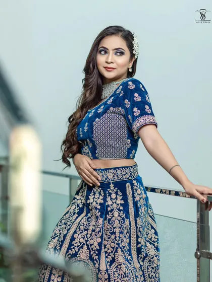 This close-up highlights the detailed embroidery on the blouse and skirt of the blue velvet lehenga, a true work of art.