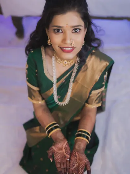A lovely high-angle shot of the bride in a green saree, showcasing her henna-adorned hands.