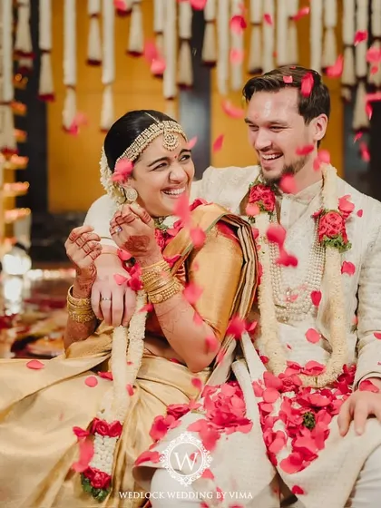 A beautiful moment from a traditional South Indian wedding. The mandap is decorated with red and white floral garlands, with rose petals showering the happy couple as they complete their rituals.
