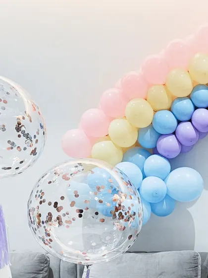 A close-up of the pastel rainbow balloon arch and the custom confetti-filled bubble balloons. The mix of colors and textures creates a soft, magical vibe.