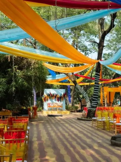 For this carnival-themed anniversary, the outdoor space was decorated with vibrant drapes in yellow, blue, and orange, creating a festive and playful atmosphere.