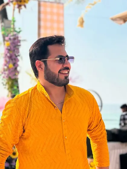 A smiling, relaxed shot at an outdoor Haldi, with the beautiful wedding decor in the background.