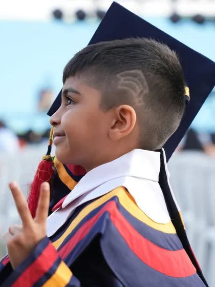 A proud graduate gives a peace sign, ready for the next chapter of his educational journey.