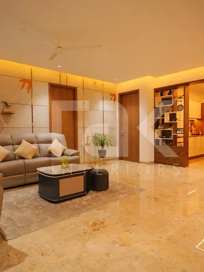A spacious living room with comfortable leather-like sofas and a large area rug. The wall panels with small, bird-like accents add a unique and artistic touch to the space.