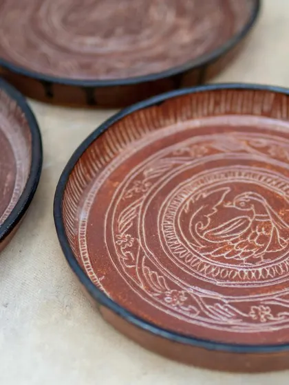 Inspired by antique bronze plates, these intricately carved ceramic plates were crafted by a student in our Foundation course. The detailed sgraffito work and rich glaze give them a timeless, heirloom quality.