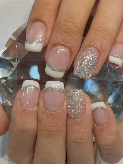 A close-up of one of our favorite designs, the glitter French manicure. This elegant style uses gel polish and extensions for a flawless finish, perfect for weddings, parties, or any special occasion.
