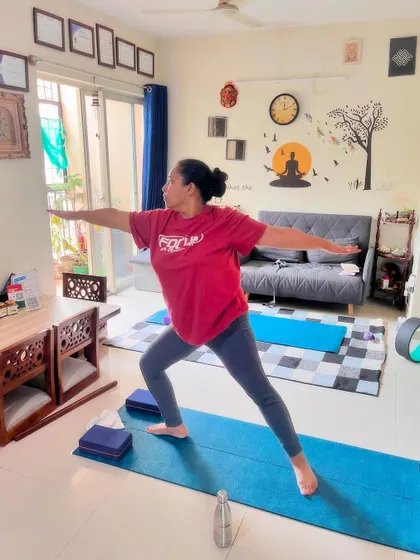 A client holds Virabhadrasana II (Warrior II), a powerful standing pose that builds strength in the legs and opens the hips and chest.