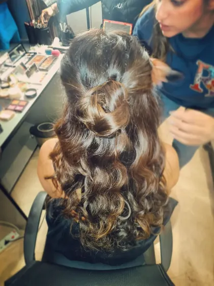 A half-up, half-down hairstyle featuring a knotted bun and soft curls. This is a trendy and youthful look, great for a pre-wedding party.