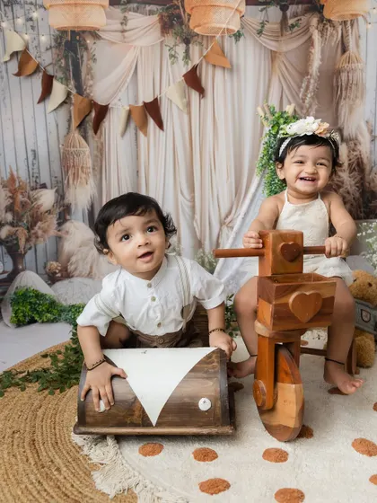 Two little ones playing with wooden toys in my boho-themed studio, a perfect setup for capturing sibling fun.