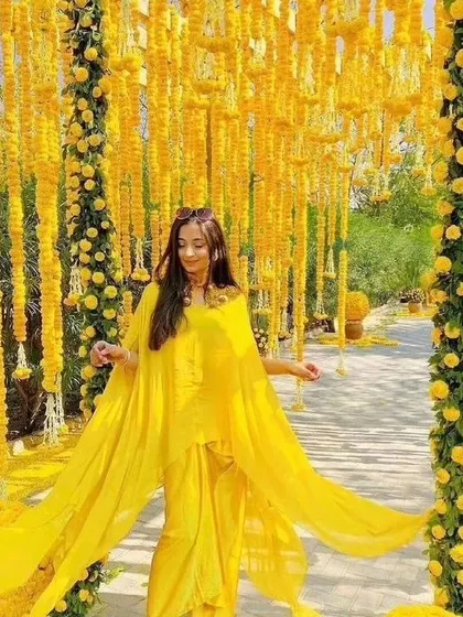 A bride enjoying her Haldi or Mehendi function in a stunning walkway decorated with hanging marigold strings. This kind of immersive decor creates fantastic photo opportunities.
