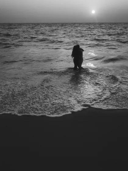 A minimalist and moody black and white shot of a couple embracing in the water. The simplicity of the composition focuses all the attention on their connection against the vastness of the sea and sky.