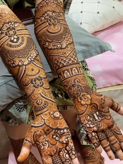 A detailed bridal design featuring bands of different patterns. You can see small elephants and floral motifs woven into the intricate artwork, with the bride's initial subtly placed on the palm.