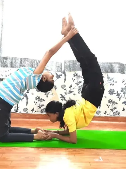 A creative partner pose combining the Camel and Tiger poses. This acro yoga formation requires one partner to hold a deep backbend while the other performs an inversion, showcasing both flexibility and strength.