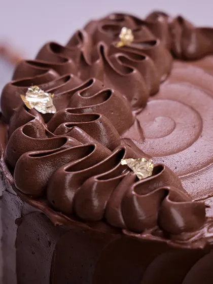 We create the ultimate indulgence with our chocolate almond cake. This rich, multi-layered chocolate cake is frosted with a silky chocolate buttercream and adorned with delicate gold leaf, offering a luxurious and classic dessert for Mother's Day.