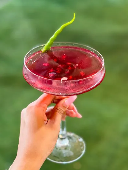 The Pomegranate Kulukki Slush is a unique mocktail with a spicy kick from a green chili garnish. The sweet and tangy pomegranate flavor is incredibly refreshing.