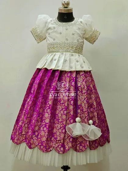 A closer look at the white and purple Banarasi silk lehenga. The intricate gold patterns on the skirt and the simple elegance of the top make this a perfect choice for matching sibling outfits.