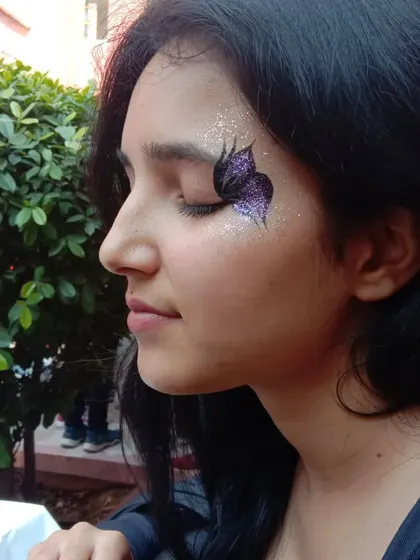 A side view of a purple glitter butterfly with a soft, blended background. The closed eyelid shows how the design looks from different angles.
