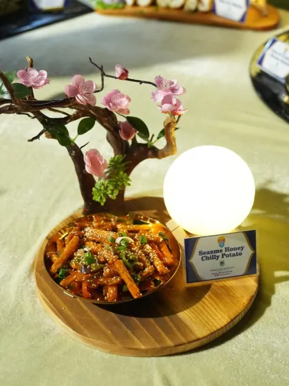 Our Sesame Honey Chilli Potato is a perfect blend of sweet, spicy, and savoury. The beautiful presentation with a cherry blossom branch makes it a visual and culinary delight.