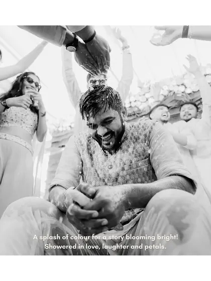 A splash of colour for a story blooming bright. This black and white shot of the groom being doused with water and petals is full of action and pure fun.