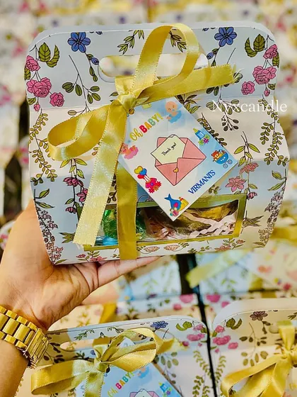 Holding one of the floral baby shower hampers, a beautiful and budget-friendly option for your event.