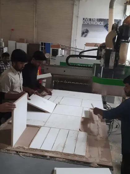 A team of students unloads a completed job from the CNC router bed. This hands-on experience with panel processing is invaluable for industry readiness.