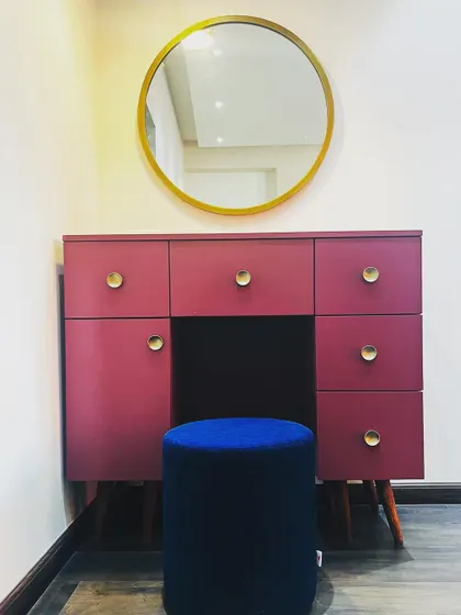 A vibrant and modern dressing table in a Gurugram home. The pop of magenta is balanced by the simple gold mirror and brass knobs, creating a chic and playful corner.