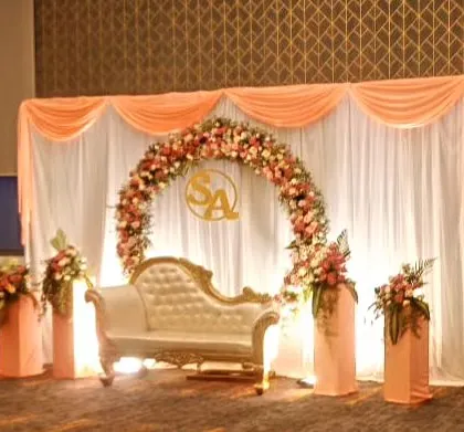 A simple and elegant floral decoration for an engagement ceremony. A floral ring, peach-colored drapes, and a classic white chaise lounge create a romantic and sophisticated ambiance.