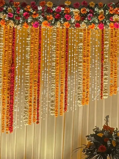 For religious or traditional ceremonies, we create beautiful backdrops using classic elements. This design features a curtain of marigold and tuberose flower strings, creating a fragrant and visually stunning setting.