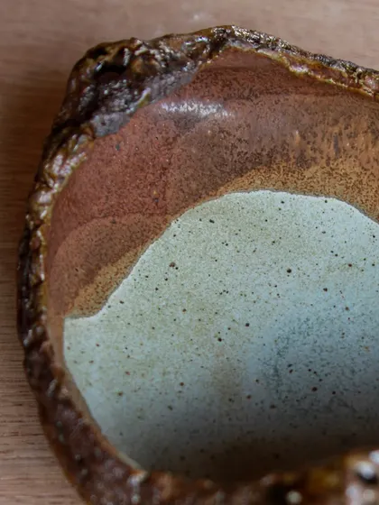 A close-up of the interior of a textured bowl, showing the beautiful color variations from the layered glazes. Each piece is a small work of art.