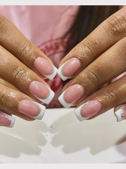 A touch of sparkle on a classic. This square-shaped French manicure is elevated with a thin line of silver glitter separating the pink base from the white tip.