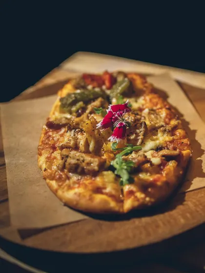 A freshly baked flatbread topped with assorted vegetables and cheese.