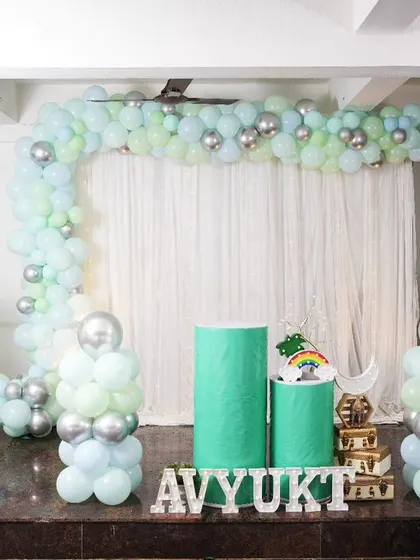 A simple and elegant decor coustamised for Avyukt's first birthday. The pastel green and silver balloon arch and modern pedestals create a clean and fresh look.