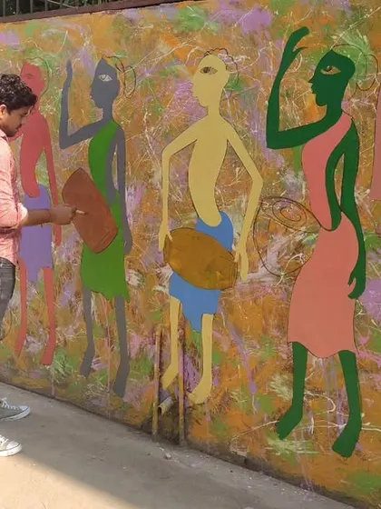 An artist working on a large-scale wall mural with a folk art theme. We also undertake public and private art commissions.